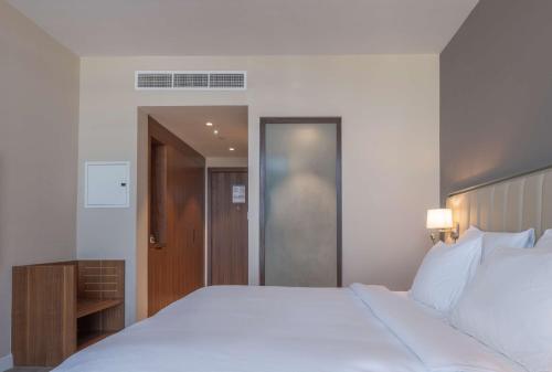 a bedroom with a large white bed and a door at Radisson Resort Ras Al Khaimah Marjan Island in Ras al Khaimah