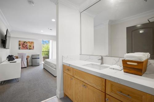 a bathroom with a sink and a large mirror at Hotel Huntington in Duarte