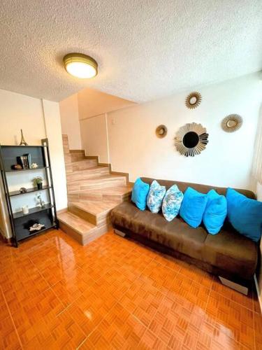 a living room with a brown couch with blue pillows at DEPTO FRENTE A ESTADIO GNP ANTES FORO SOL y AUTODROMO F1 A 10 MIN CAMINANDO in Mexico City