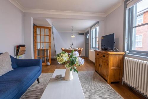 a living room with a blue couch and a tv at Sailmaker's Cottage in Lymington