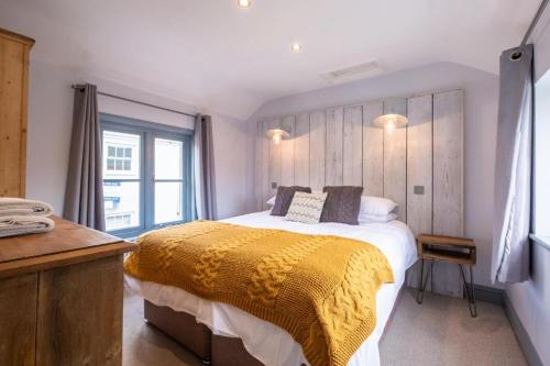 um quarto com uma cama grande e um cobertor amarelo em Sailmaker's Cottage em Lymington