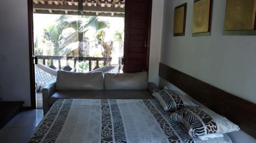 a bed in a room with a couch and a window at Sol da Pipa Flat Condominio La Piazzeta in Pipa