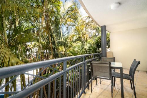 a balcony with a table and chairs and palm trees at Turtle Beach Resort in Gold Coast
