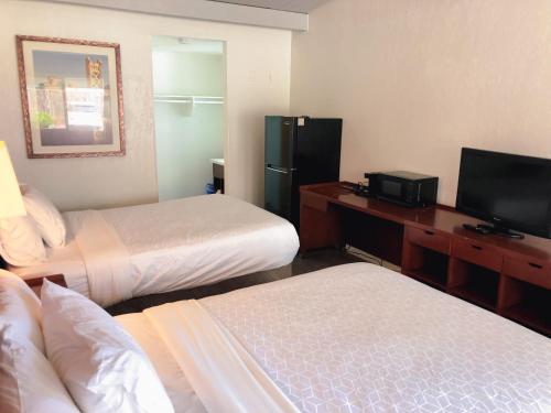 una camera d'albergo con due letti e una televisione di Extended Studio Suites a San Jose