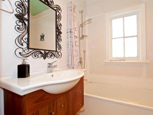a bathroom with a sink and a mirror and a tub at The Lazy Carrot - Ohakune Holiday Home in Ohakune