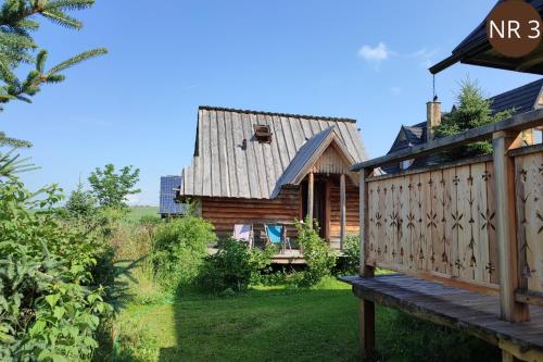 a log cabin with a porch and a deck at Miętowa Osada Czerwienne in Ciche