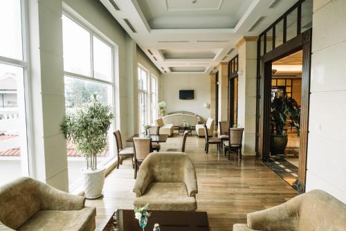 un vestíbulo con sillas, mesas y ventanas en La Sapinette Hotel Dalat, en Da Lat