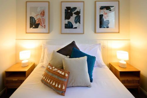 a bed with pillows and three pictures on the wall at Georges Bay Apartments in St Helens