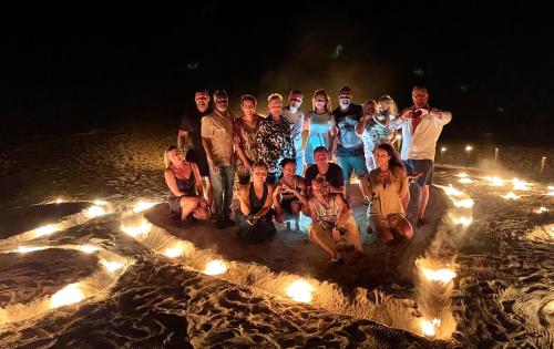 a group of people standing in a circle with lights at Three Hearts Guesthouse and Villas in Fulhadhoo