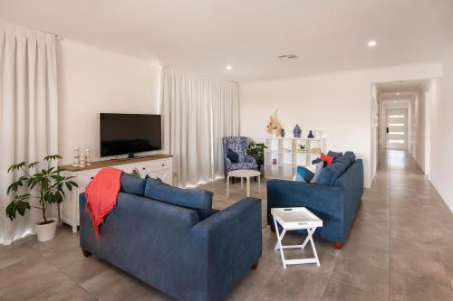 a living room with two blue couches and a tv at Meadows in Dunsborough