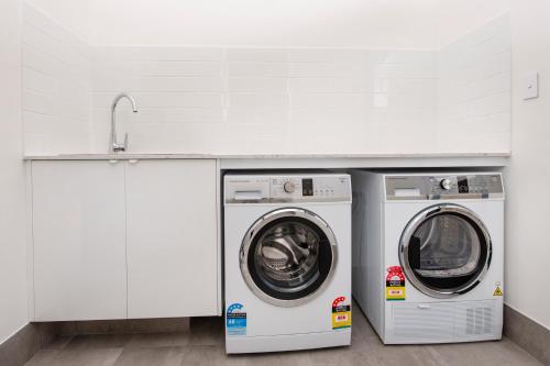 two washing machines and a sink in a laundry room at Meadows in Dunsborough
