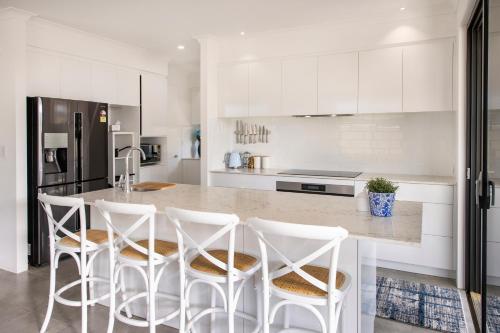 a kitchen with white cabinets and a counter with stools at Meadows in Dunsborough