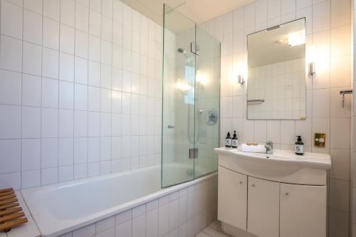 a bathroom with a tub and a sink and a shower at Sunshine On The Beach at The Sands in Onetangi