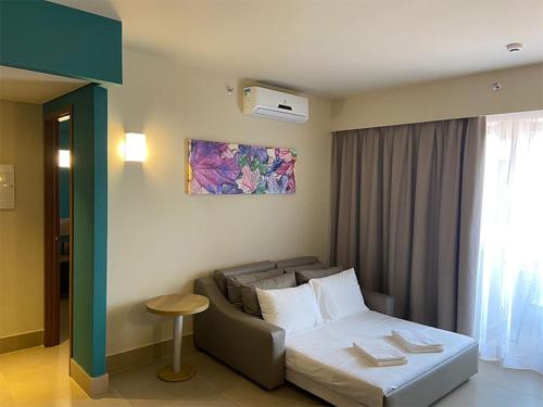 um quarto de hotel com uma cama e um sofá em Resort Olimpia Apartamento em Olímpia