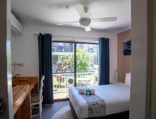 a bedroom with a bed and a large window at OCEAN BREEZE MOTEL in Port Macquarie