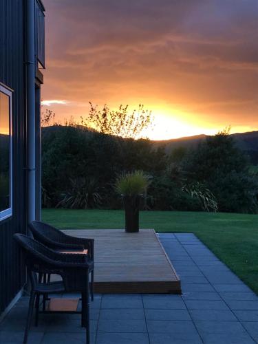 a patio with a bench and a sunset in the background at Maungatautari Outlook Cambridge in Cambridge