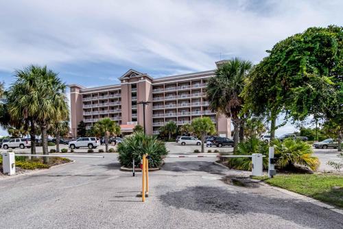 un gran edificio rosa con palmeras delante en The Dunes, en Gulf Shores