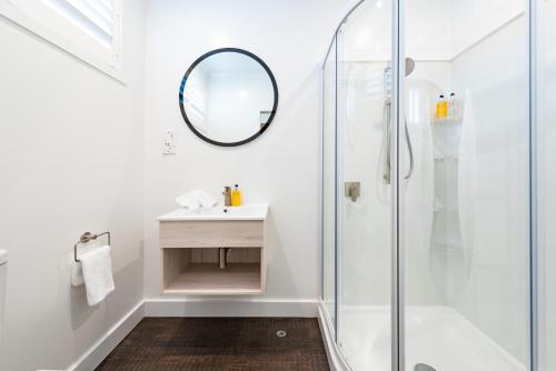 a bathroom with a shower and a sink and a mirror at Suncourt Hotel & Conference Centre in Taupo