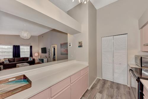 a kitchen with white cabinets and a living room at Jellyfish-Flamingo House, Amazing Location On Beach & Walk To Village in Siesta Key