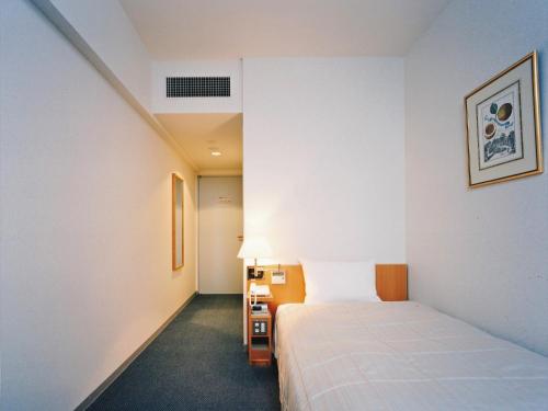 a hotel room with a bed and a lamp at 湘南リリーフ in Yokosuka