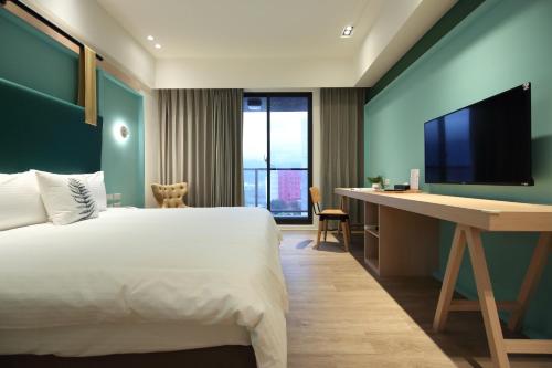 a bedroom with a bed and a desk with a television at Hai Sheng Wei B&B in Dahan
