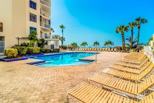 a swimming pool with lounge chairs and palm trees at Beach Palms in Clearwater Beach