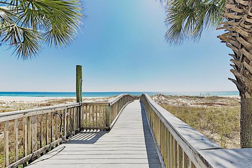 a boardwalk to the beach with a palm tree at SeaSpray East E0122 in Perdido Key