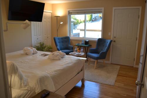 a bedroom with two chairs and a bed and a window at Salish B&B and Spa in West Kelowna