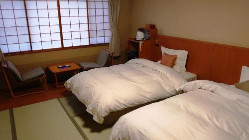 a hotel room with two beds and a window at Takinoya Bekkan Tamanoyu in Noboribetsu