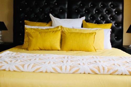 a bed with yellow pillows and a black headboard at Coffee Bay Lodge in Coffee Bay