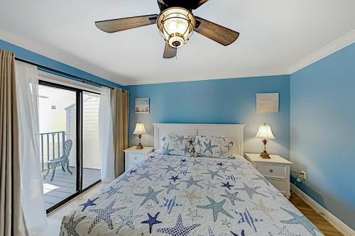 1 dormitorio con 1 cama con paredes azules y ventilador de techo en Bay View Villas #118 en Clearwater Beach