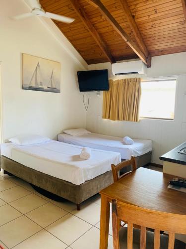 two beds in a room with a desk and a table at Airlie Beach Apartments in Airlie Beach
