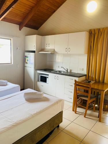 a kitchen with white cabinets and a table and a bed at Airlie Beach Apartments in Airlie Beach