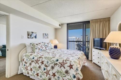 a bedroom with a bed and a television and a balcony at Sea Watch Condos III in Ocean City