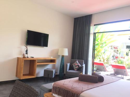 a hotel room with a bed and a desk and a television at Le Chien Rouge in Lovina