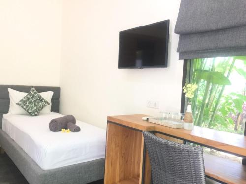 a small room with a desk and a bed and a television at Le Chien Rouge in Lovina