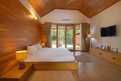 a bedroom with a bed and a television in it at StayVista at Tall Silver with Infinity Pool & Breakast in Madikeri