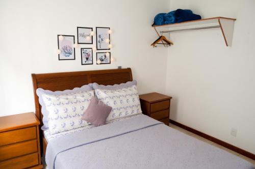 um quarto com uma cama e algumas fotografias na parede em Apartamento aconchegante em Petrópolis