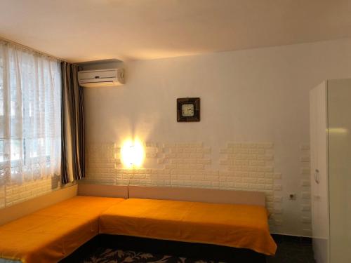 ein Schlafzimmer mit einem orangenen Bett mit einer Uhr an der Wand in der Unterkunft Боксониера Georgi Georgiev in Warna