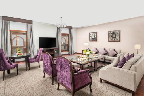 a living room with purple furniture and a tv at Taiba Front Hotel in Al Madinah