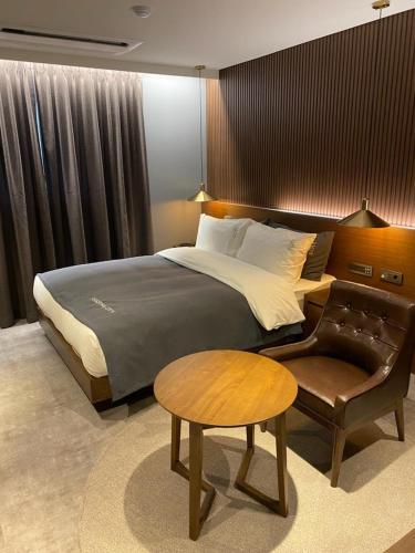 a bedroom with a bed and a chair and a table at Anseong City Hotel in Anseong