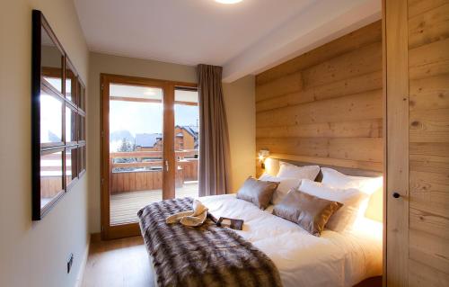 a bedroom with a bed with a wooden wall at Odalys Chalet Chambertin Lodge in Les Deux Alpes