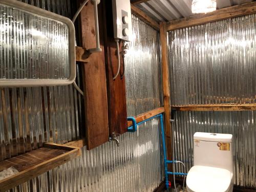 uma casa de banho com um WC numa parede de metal em Mondulkiri Pizza Bungalows em Sen Monorom