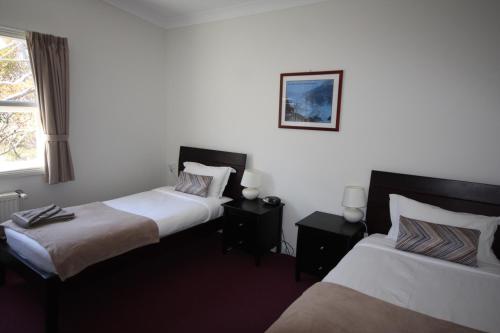 two beds in a room with white walls at The Lions Lair Lodge in Smiggin Holes