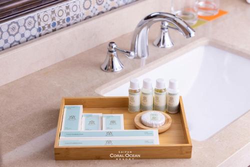 a wooden tray with four bottles of cosmetics on a sink at Coral Ocean Resort in Saipan