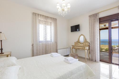 a white bedroom with a bed and a view of the ocean at Agapi Villas I & II, Seaside Retreats with Pool & BBQ, By ThinkVilla in Panormos Rethymno