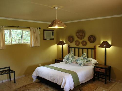 a bedroom with a bed with two lamps on it at Sandforest Cottages in Hluhluwe