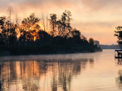a misty sunrise on a lake with trees and a boat at Hotel Yeti in Pokhara