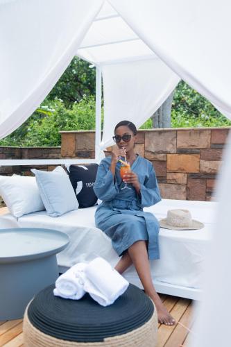 a woman sitting on a bed drinking a drink at The Capital Zimbali in Ballito