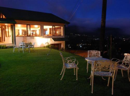 a group of chairs and a table in a yard at night at Tea Bush Hotel in Nuwara Eliya